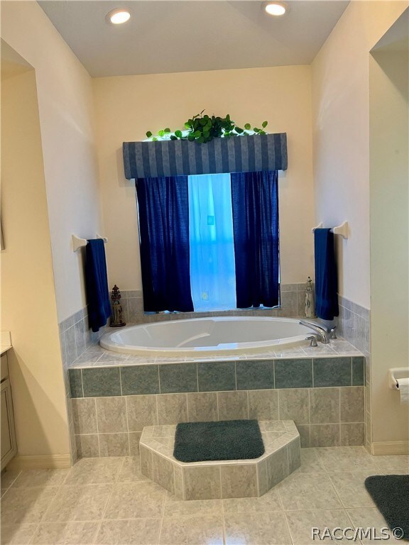 bathroom featuring tile patterned flooring, vanity, and tiled tub