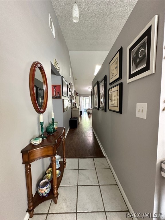 corridor featuring light hardwood / wood-style floors and a textured ceiling