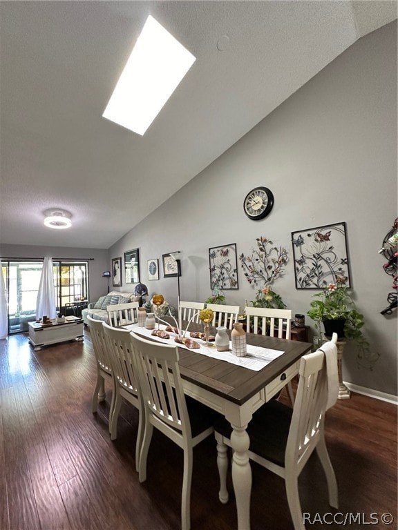 dining room with dark hardwood / wood-style flooring and lofted ceiling with skylight