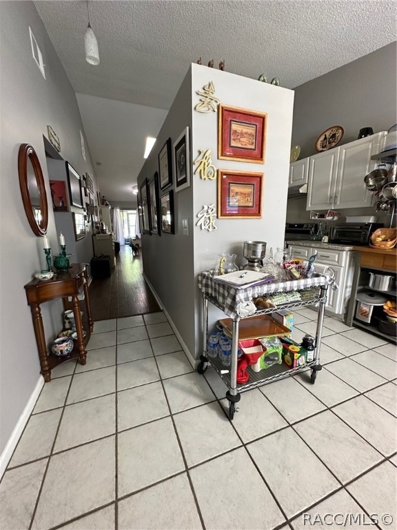 hall with light tile patterned floors and a textured ceiling