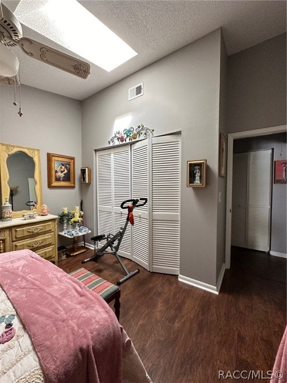 bedroom featuring a skylight, dark hardwood / wood-style flooring, and a textured ceiling