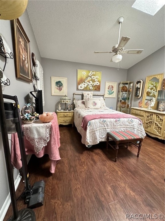 bedroom featuring a textured ceiling, a skylight, ceiling fan, and dark hardwood / wood-style floors