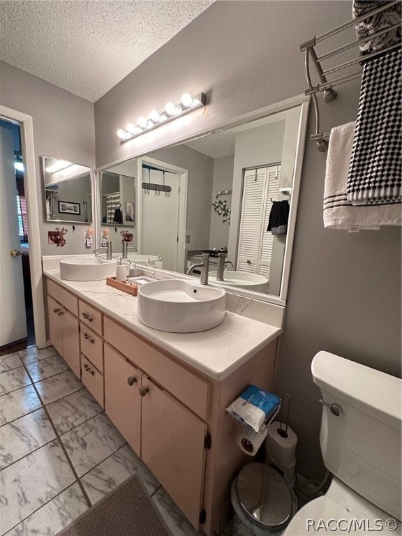 bathroom featuring vanity, a textured ceiling, and toilet