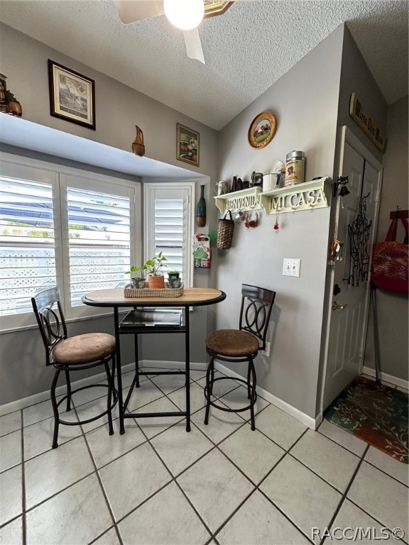 dining area featuring tile patterned flooring, ceiling fan, and a textured ceiling