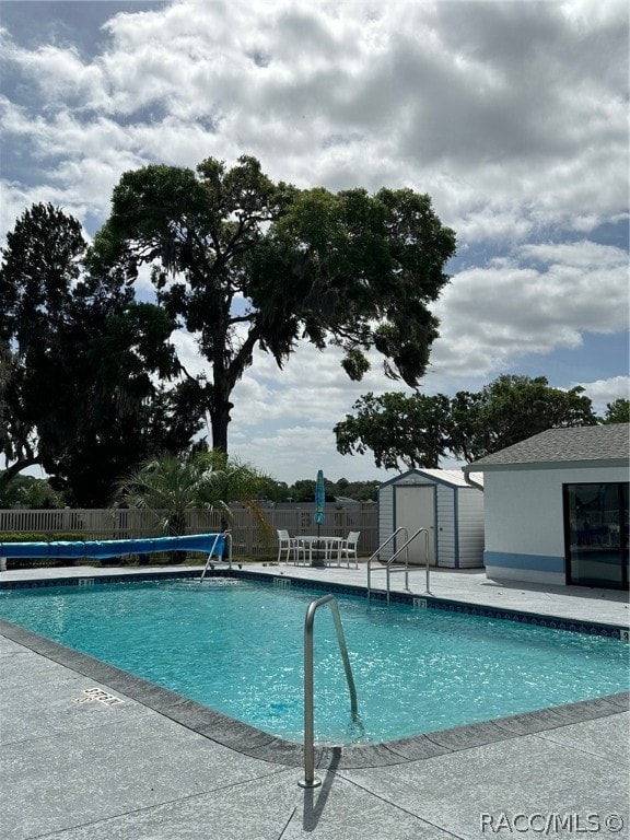 view of pool featuring a shed and a patio