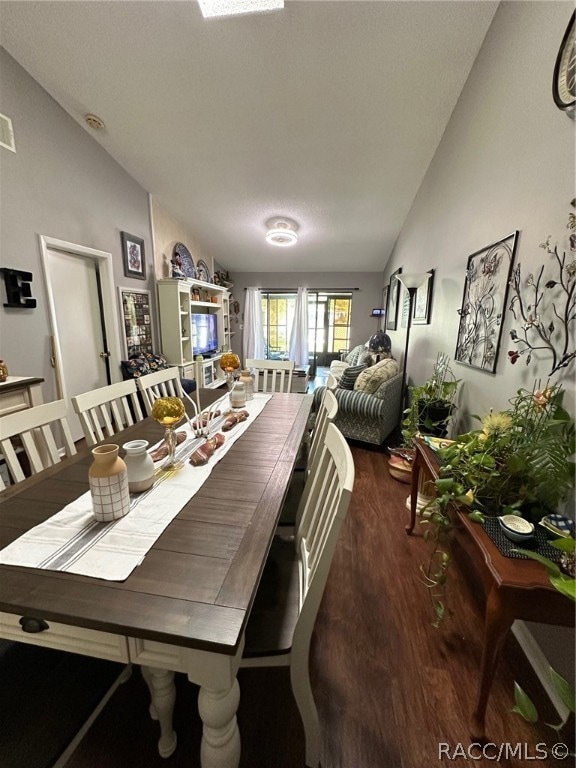 dining space featuring dark hardwood / wood-style floors and lofted ceiling