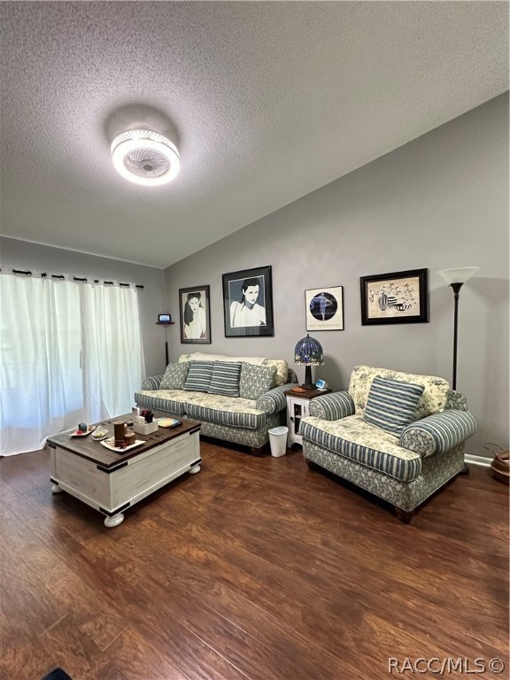 living room with lofted ceiling, dark wood-type flooring, and a textured ceiling