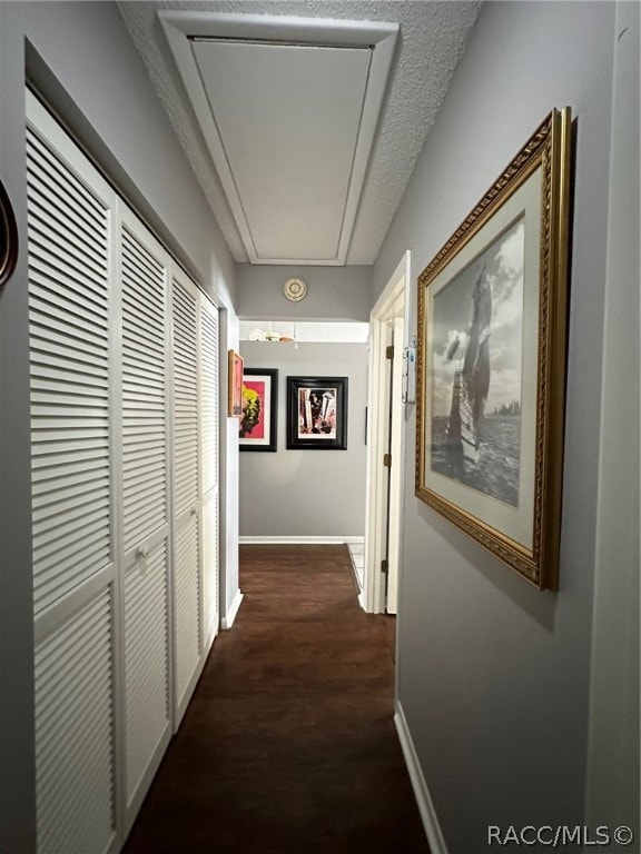 hall featuring a textured ceiling and dark wood-type flooring