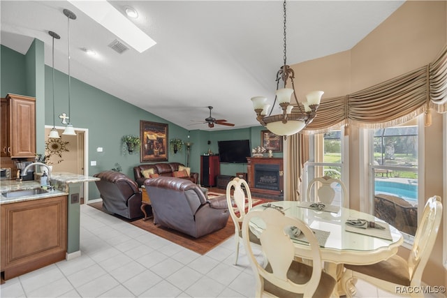 dining space with light tile patterned flooring, ceiling fan with notable chandelier, vaulted ceiling, and sink