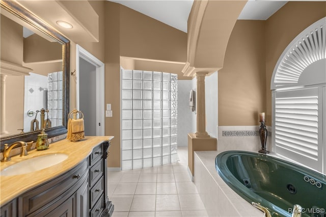 bathroom featuring ornate columns, tile patterned floors, tiled bath, vaulted ceiling, and vanity