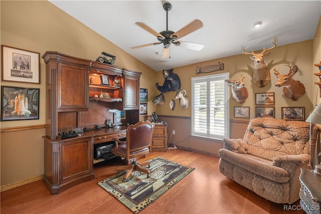 office space with a textured ceiling, vaulted ceiling, light hardwood / wood-style flooring, and ceiling fan