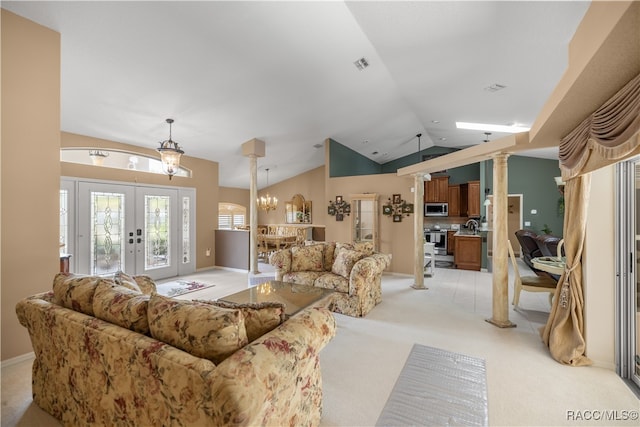 carpeted living room with french doors, an inviting chandelier, vaulted ceiling, and decorative columns