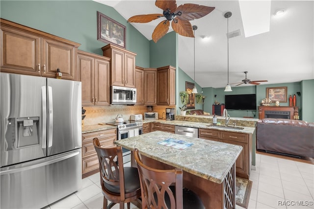 kitchen with a kitchen bar, appliances with stainless steel finishes, pendant lighting, and sink