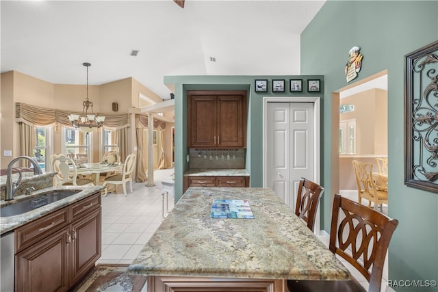 dining room featuring sink, light tile patterned floors, lofted ceiling, and an inviting chandelier