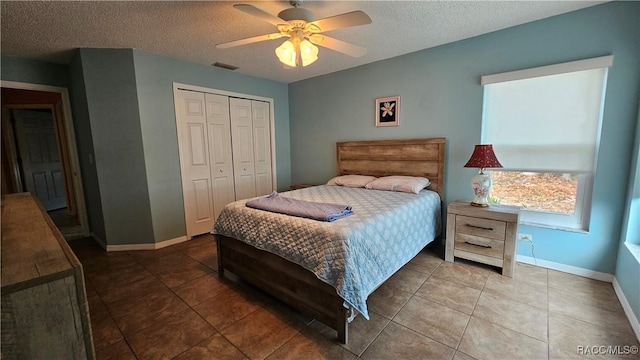 bedroom with tile patterned flooring, ceiling fan, a closet, and a textured ceiling