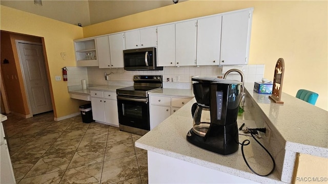 kitchen with white cabinetry, appliances with stainless steel finishes, kitchen peninsula, light stone countertops, and decorative backsplash