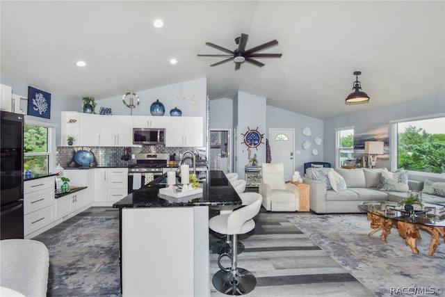 kitchen with backsplash, a breakfast bar area, vaulted ceiling, white cabinetry, and stainless steel appliances