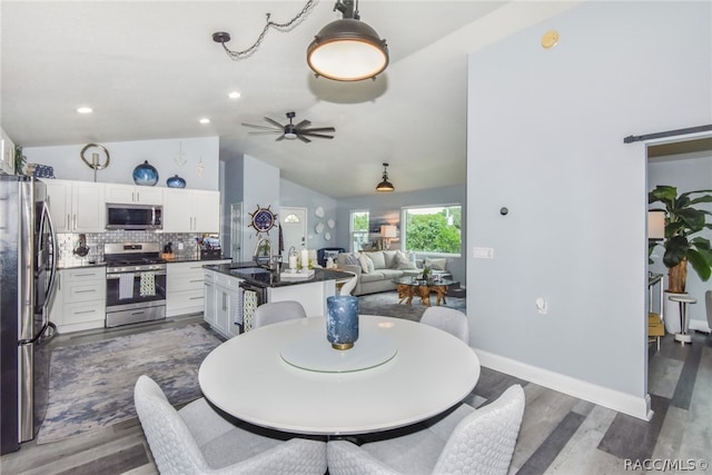 dining room with ceiling fan, dark hardwood / wood-style flooring, sink, and vaulted ceiling