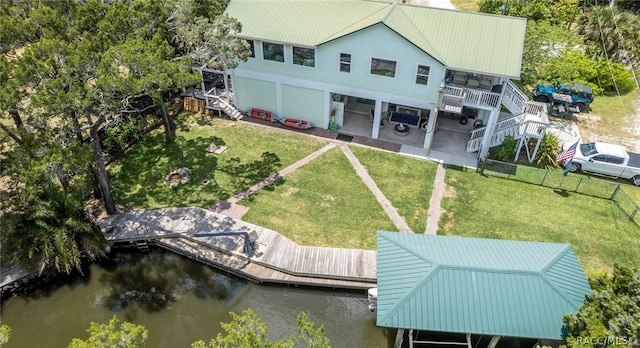 back of property with a lawn, a patio area, and a deck with water view