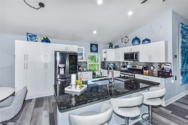 kitchen with appliances with stainless steel finishes, dark hardwood / wood-style flooring, sink, white cabinets, and lofted ceiling