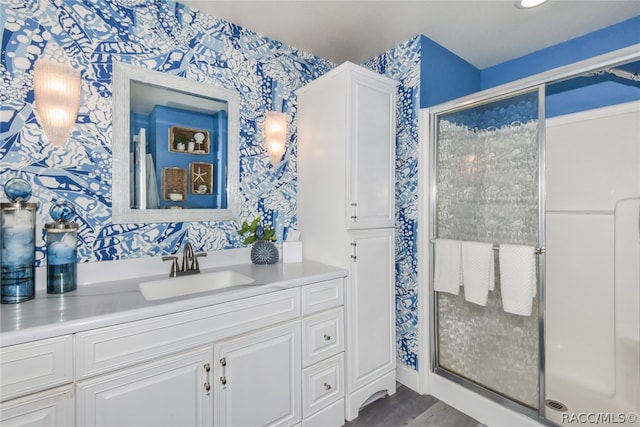 bathroom with hardwood / wood-style floors, vanity, and an enclosed shower