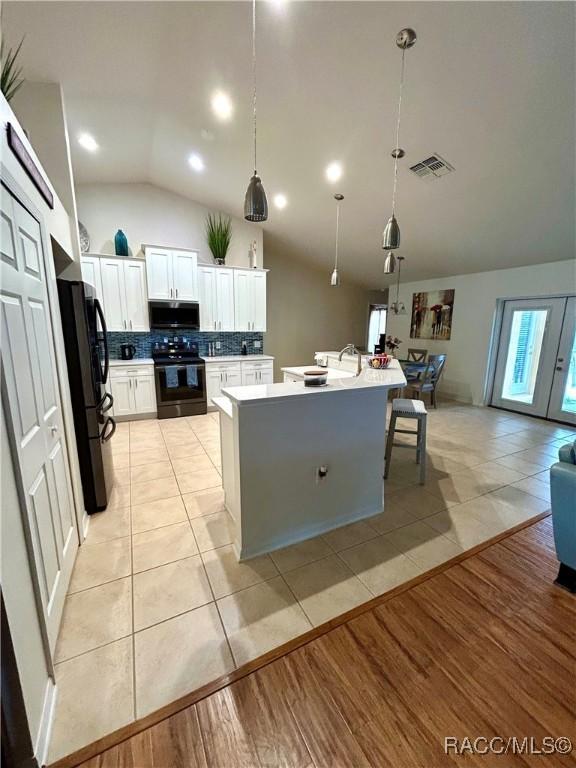 3495 W Wilburton Dr, Citrus Springs, FL 34433 - kitchen with black appliances, vaulted ceiling, light tile patterned floors, white cabinets, and light countertops