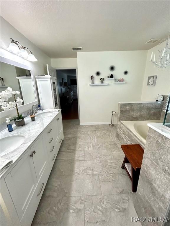 3495 W Wilburton Dr, Citrus Springs, FL 34433 - full bathroom featuring double vanity, a bath, marble look tiles, and a textured ceiling