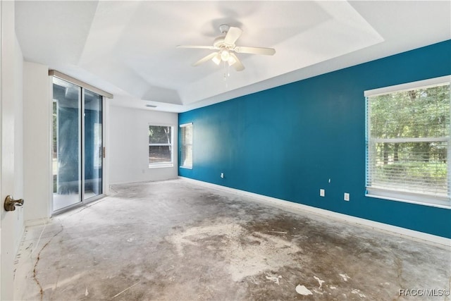 unfurnished room featuring ceiling fan, a raised ceiling, and concrete flooring