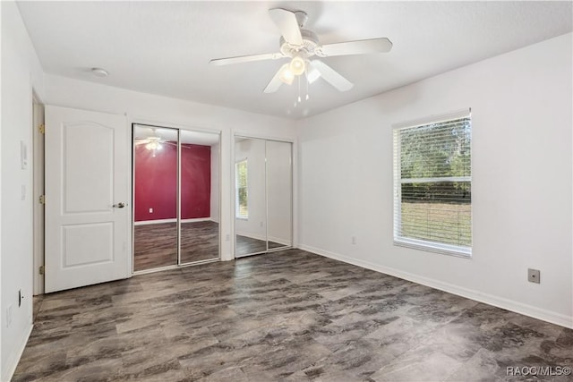 unfurnished bedroom with ceiling fan and two closets