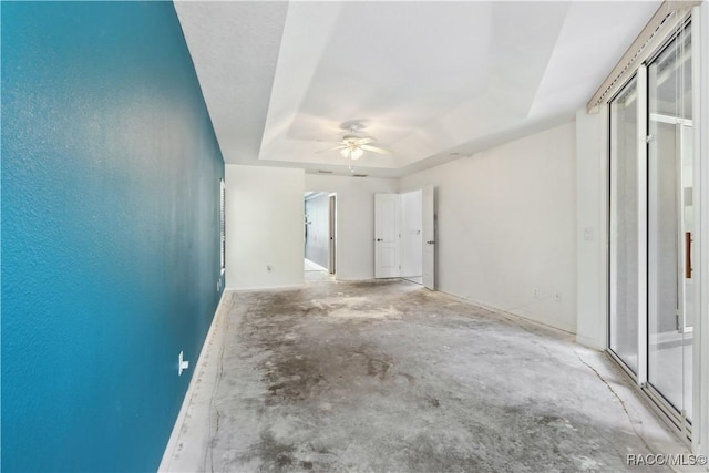 unfurnished room featuring a raised ceiling and ceiling fan