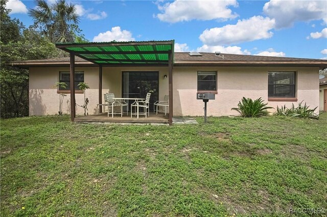 4055 N Little Hawk Pt, Crystal River, FL 34428 - back of house with stucco siding, a patio area, and a lawn