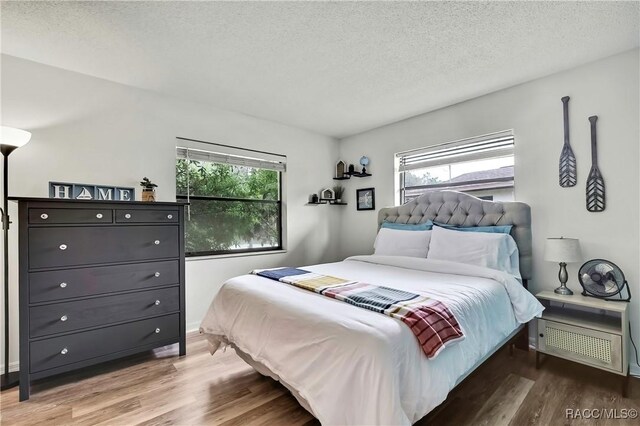 4055 N Little Hawk Pt, Crystal River, FL 34428 - bedroom with a textured ceiling, multiple windows, and wood finished floors