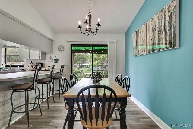 4055 N Little Hawk Pt, Crystal River, FL 34428 - dining area with baseboards, wood finished floors, vaulted ceiling, and a notable chandelier