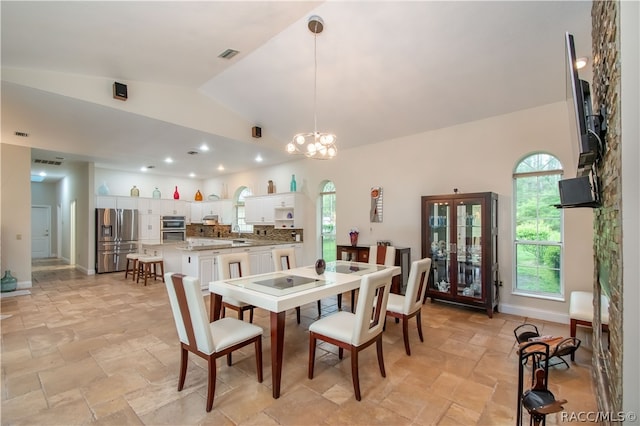 dining area featuring high vaulted ceiling and a notable chandelier