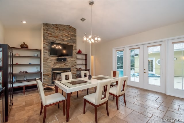 dining area with a notable chandelier, a large fireplace, high vaulted ceiling, and french doors