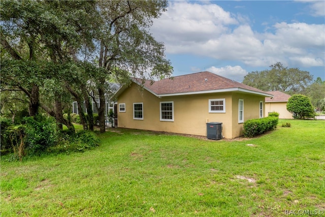 back of property with central air condition unit and a yard