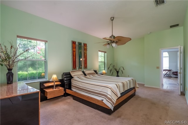 bedroom featuring multiple windows, light carpet, and ceiling fan