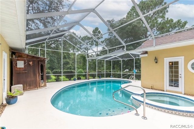 view of swimming pool featuring glass enclosure, an in ground hot tub, and a patio