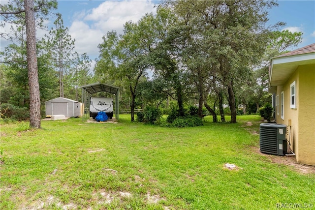 view of yard with central air condition unit, a carport, and a storage shed