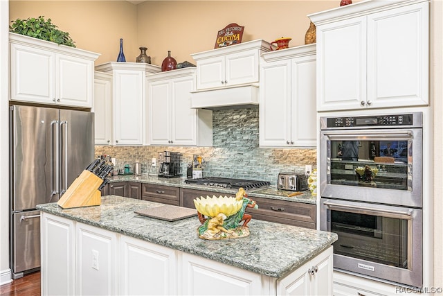 kitchen with light stone countertops, dark hardwood / wood-style flooring, decorative backsplash, white cabinets, and appliances with stainless steel finishes