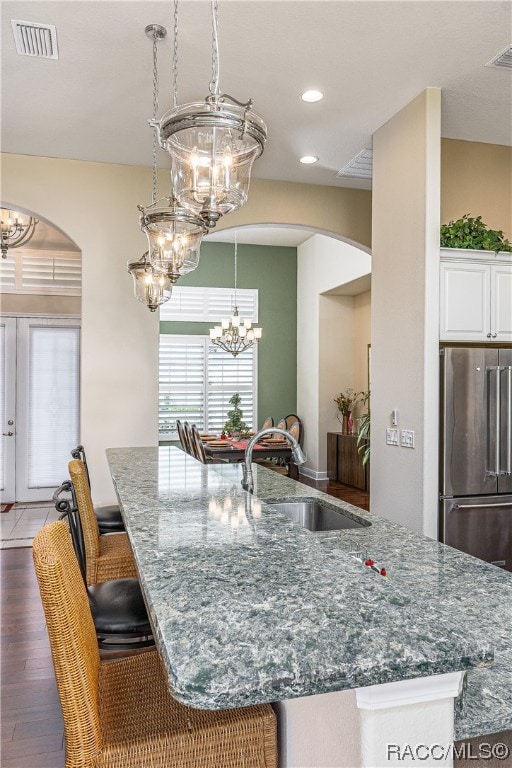 kitchen with stainless steel fridge, sink, stone counters, dark hardwood / wood-style floors, and white cabinetry