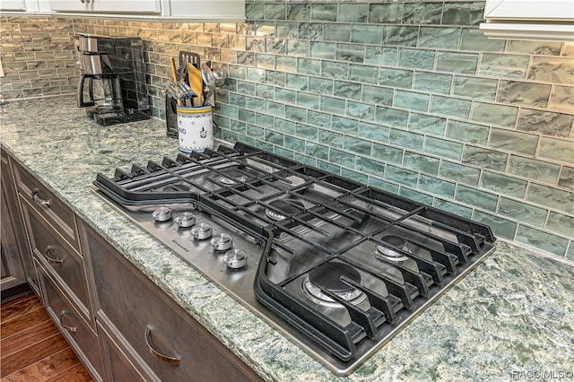 room details featuring backsplash, dark brown cabinets, dark hardwood / wood-style floors, and gas cooktop