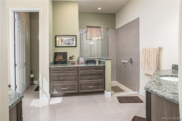 bathroom with tile patterned flooring, vanity, and a tile shower