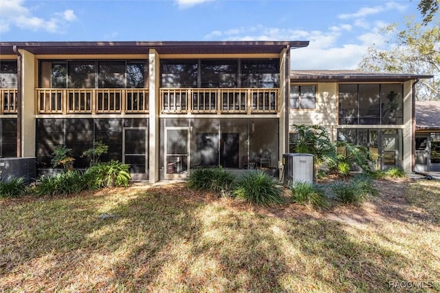 rear view of property with central AC unit and a lawn