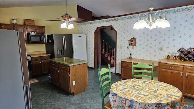 kitchen featuring ceiling fan with notable chandelier, vaulted ceiling, black appliances, pendant lighting, and a kitchen island