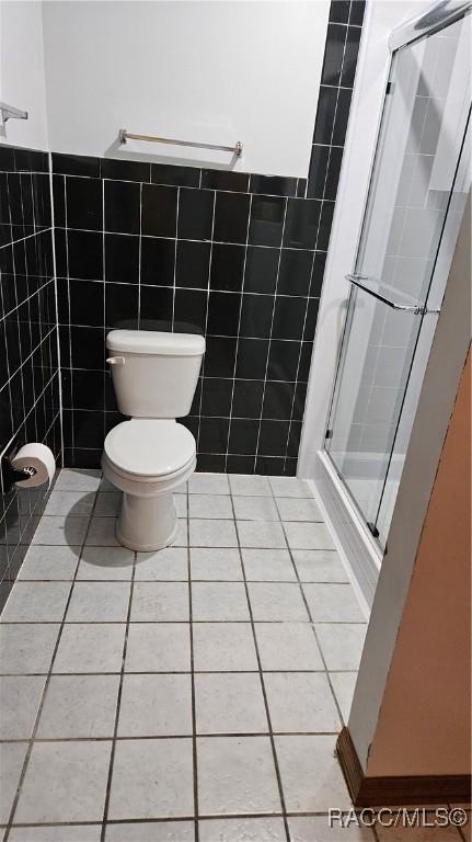 bathroom featuring tile walls, tile patterned floors, toilet, and walk in shower