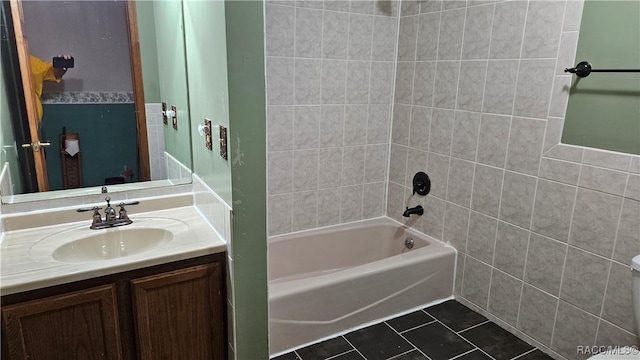 bathroom featuring tile patterned flooring, tiled shower / bath, and vanity