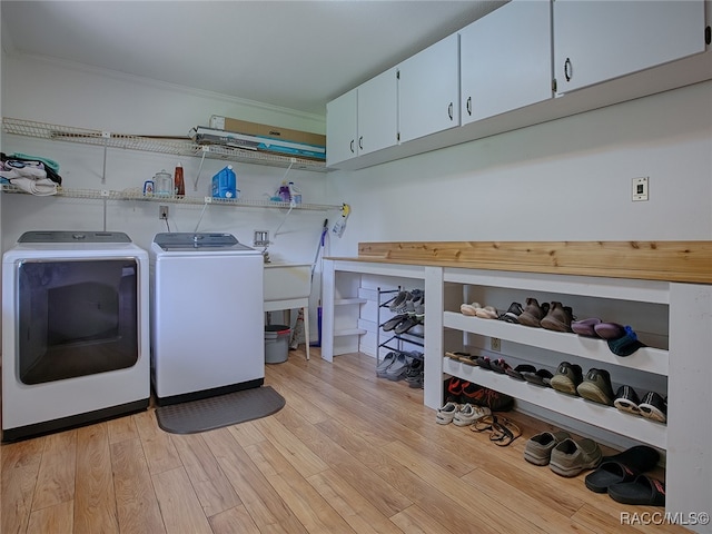 laundry room featuring washer and dryer, crown molding, cabinets, and light wood-type flooring