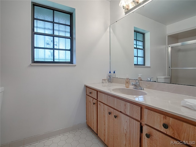 bathroom with tile patterned floors, vanity, toilet, and a healthy amount of sunlight