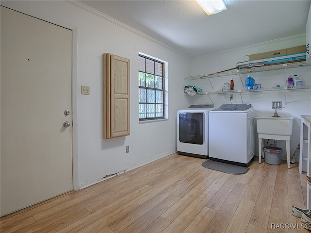 washroom with light hardwood / wood-style floors, washer and clothes dryer, and crown molding